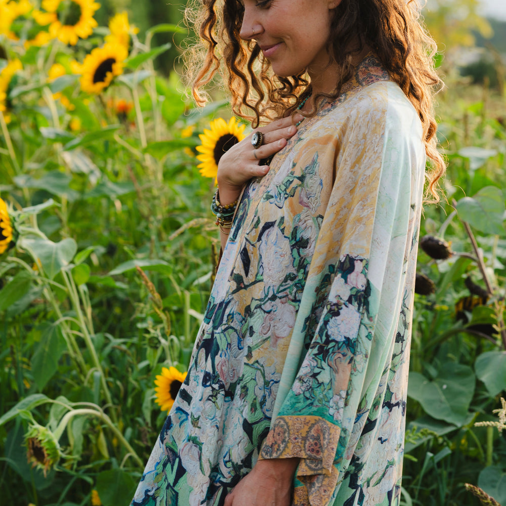
                  
                    Model wearing long kimono duster featuring Van Gogh artwork and quote, with painted blossoms, book, sun, and eye in rich tones of jade and gold - Market of Stars
                  
                