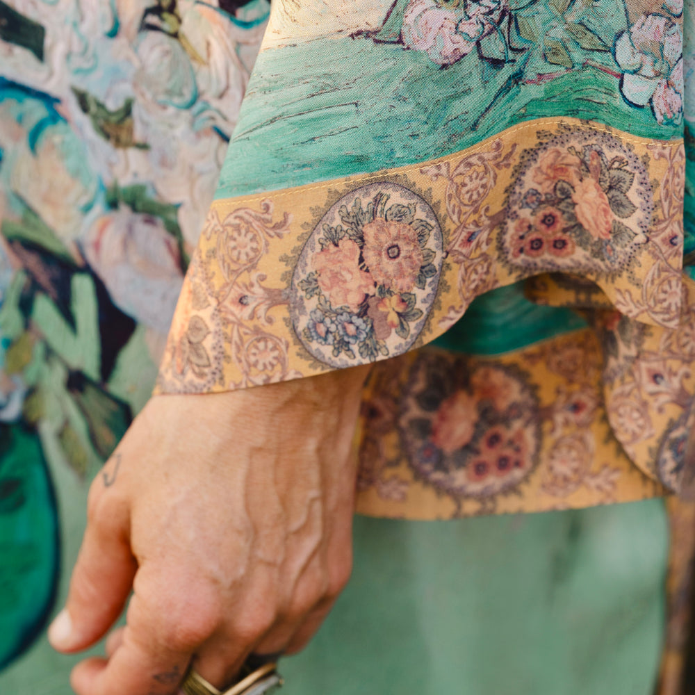 
                  
                    Model wearing long kimono duster featuring Van Gogh artwork and quote, with painted blossoms, book, sun, and eye in rich tones of jade and gold - Market of Stars
                  
                