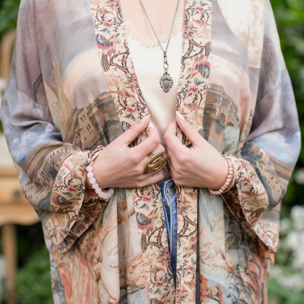 
                  
                    Model wearing the Imaginarium matinee duster featuring a dreamy collage of historic art, candle chandelier, and sleeping muse inspired by Victorian paintings – Market of Stars
                  
                