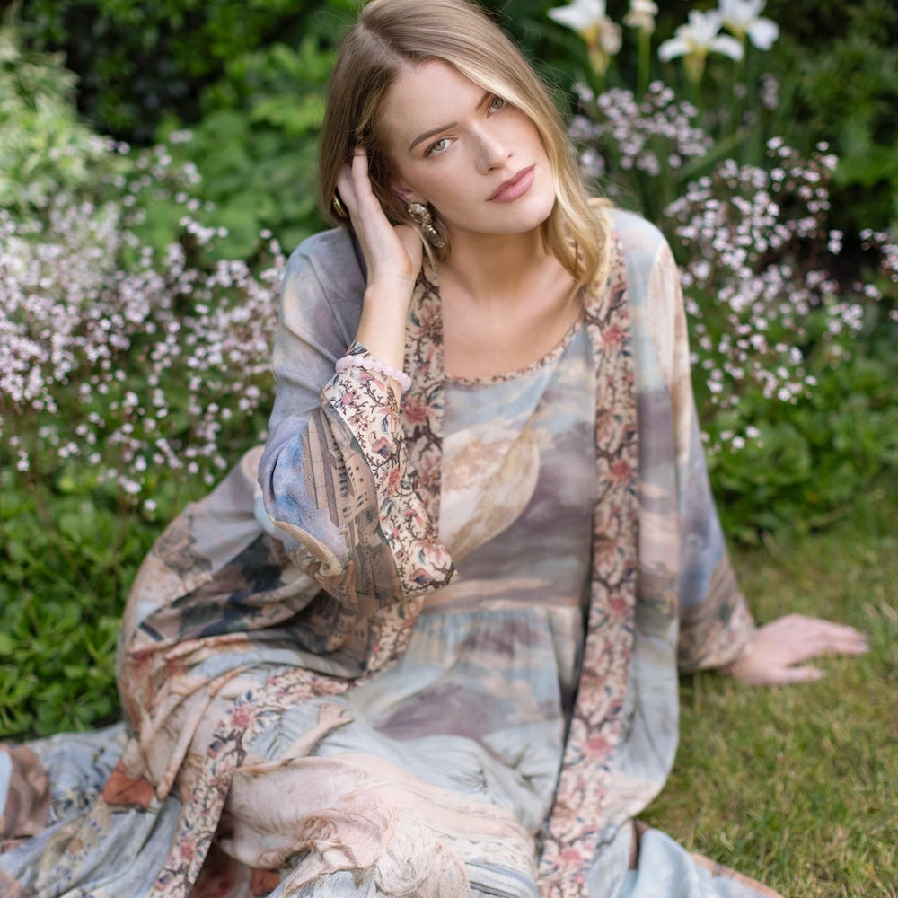
                  
                    Model standing in airy Imaginarium opera duster featuring layered dreamscape art, candlelit chandelier, and sleeping muse inspired by Victorian paintings – Market of Stars
                  
                