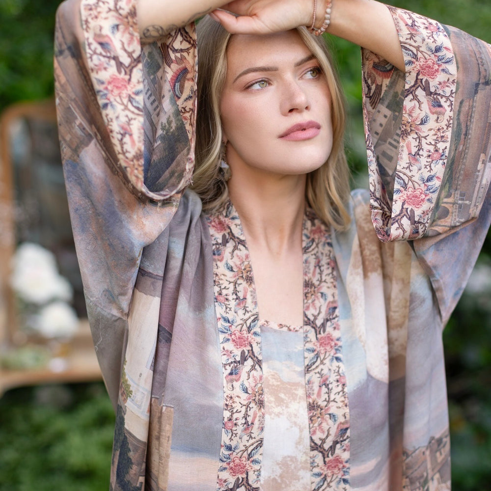 
                  
                    Model standing in airy Imaginarium opera duster featuring layered dreamscape art, candlelit chandelier, and sleeping muse inspired by Victorian paintings – Market of Stars
                  
                