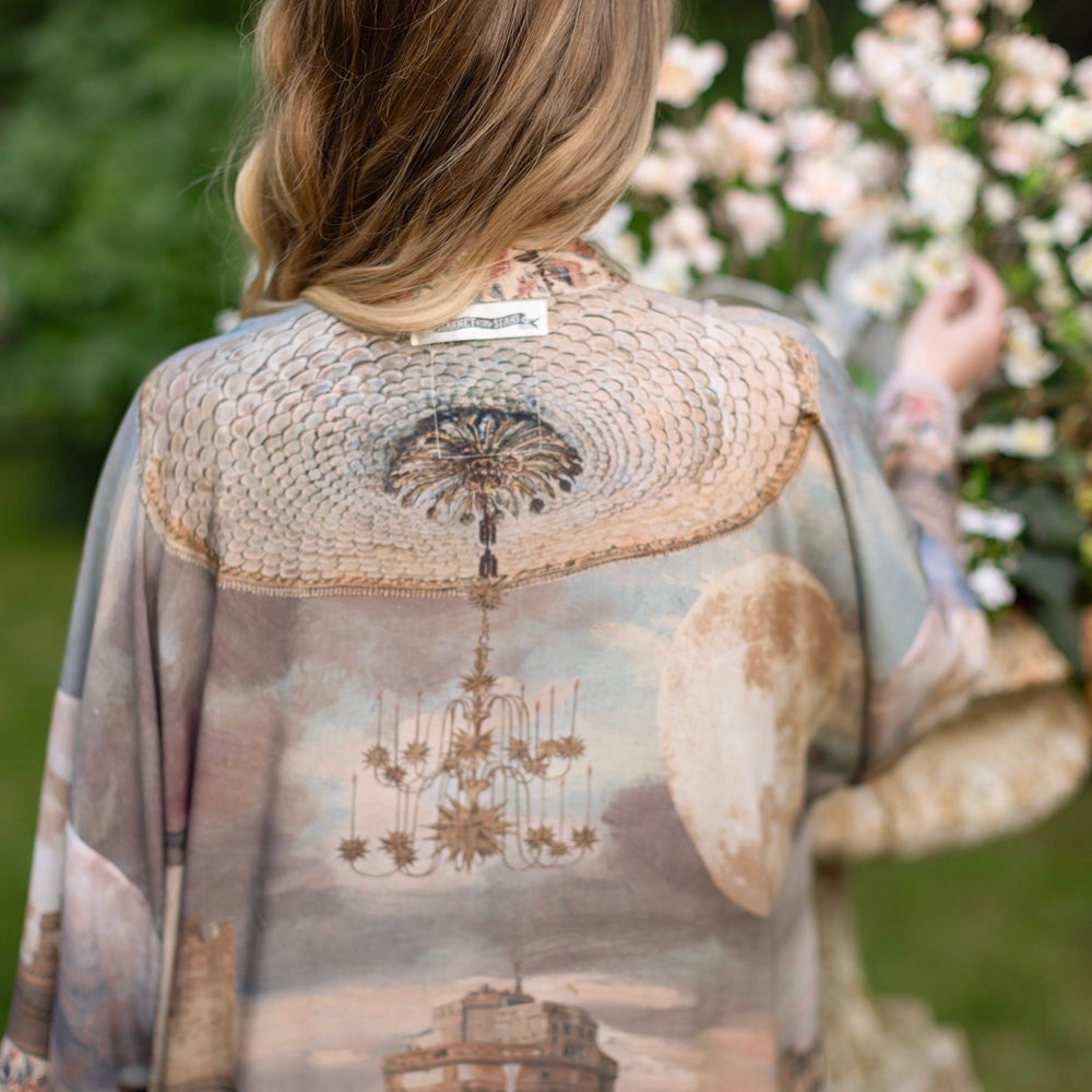 
                  
                    Model standing in airy Imaginarium opera duster featuring layered dreamscape art, candlelit chandelier, and sleeping muse inspired by Victorian paintings – Market of Stars
                  
                