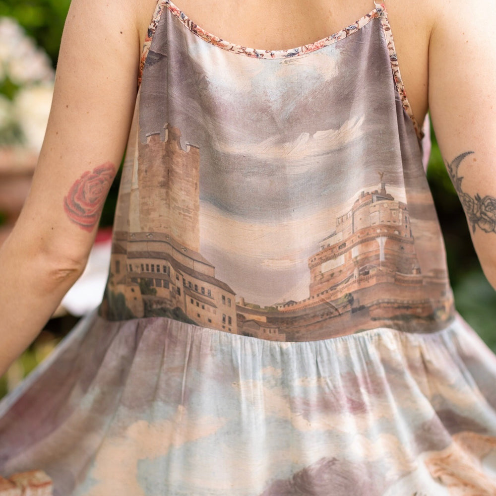 
                  
                    Model wearing the Imaginarium Bohéme Slip Dress featuring a dreamy layered print of historic landscapes, chandeliers, and a sleeping muse – Market of Stars.
                  
                