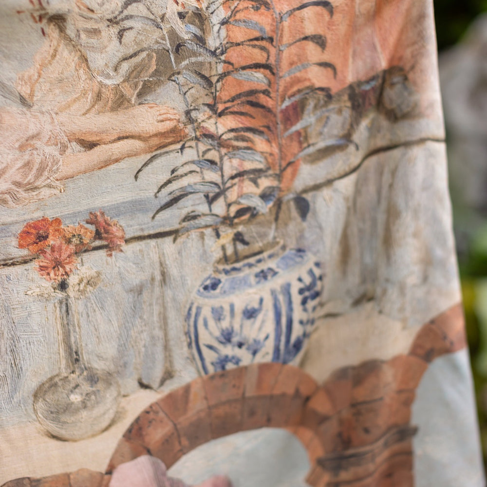
                  
                    Model wearing the Imaginarium Bohéme Slip Dress featuring a dreamy layered print of historic landscapes, chandeliers, and a sleeping muse – Market of Stars.
                  
                