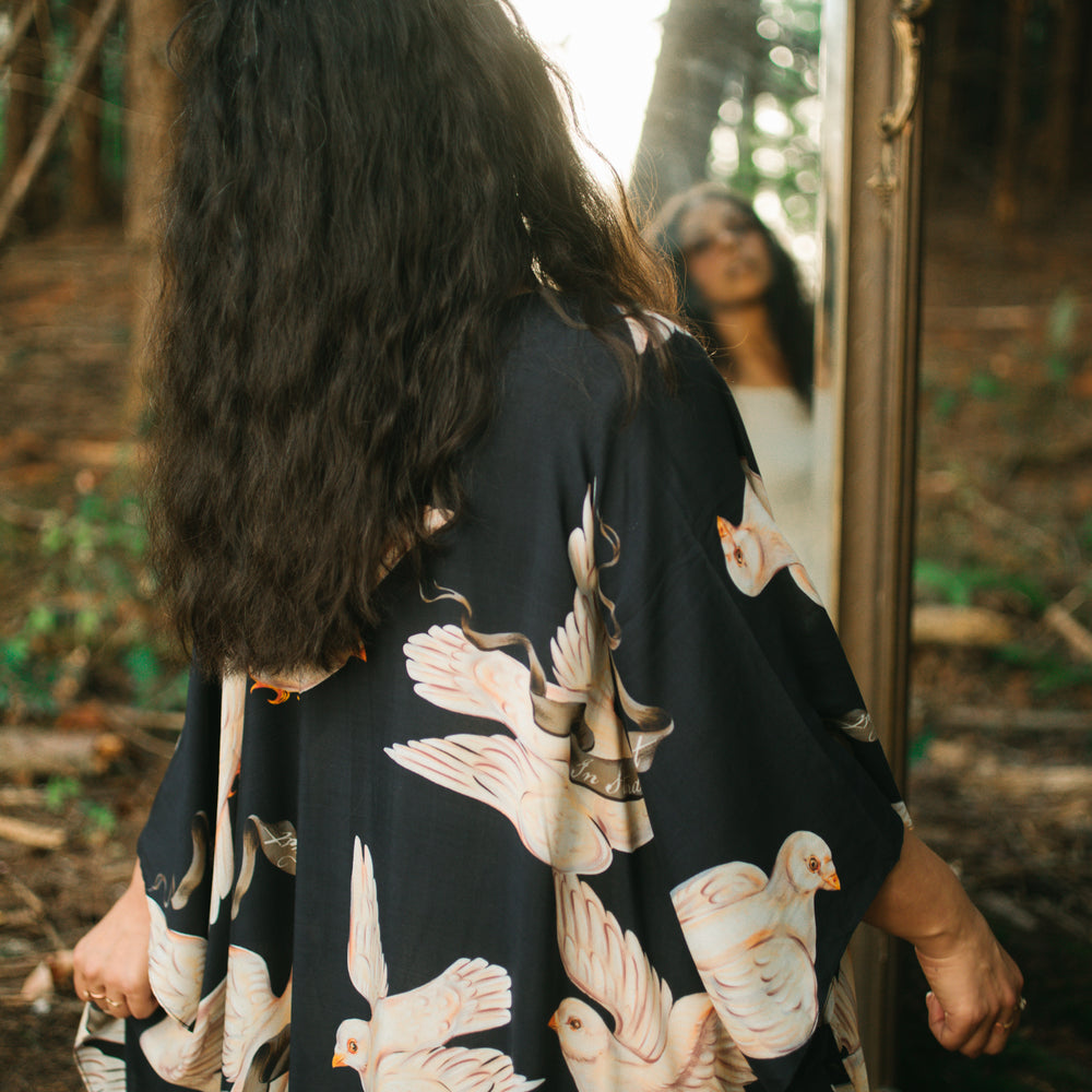 
                  
                    Model wearing the original Market of Stars kimono featuring Victorian-inspired doves and the words “In Stardust We Trust” — a tribute to dreams and possibility – Market of Stars.
                  
                