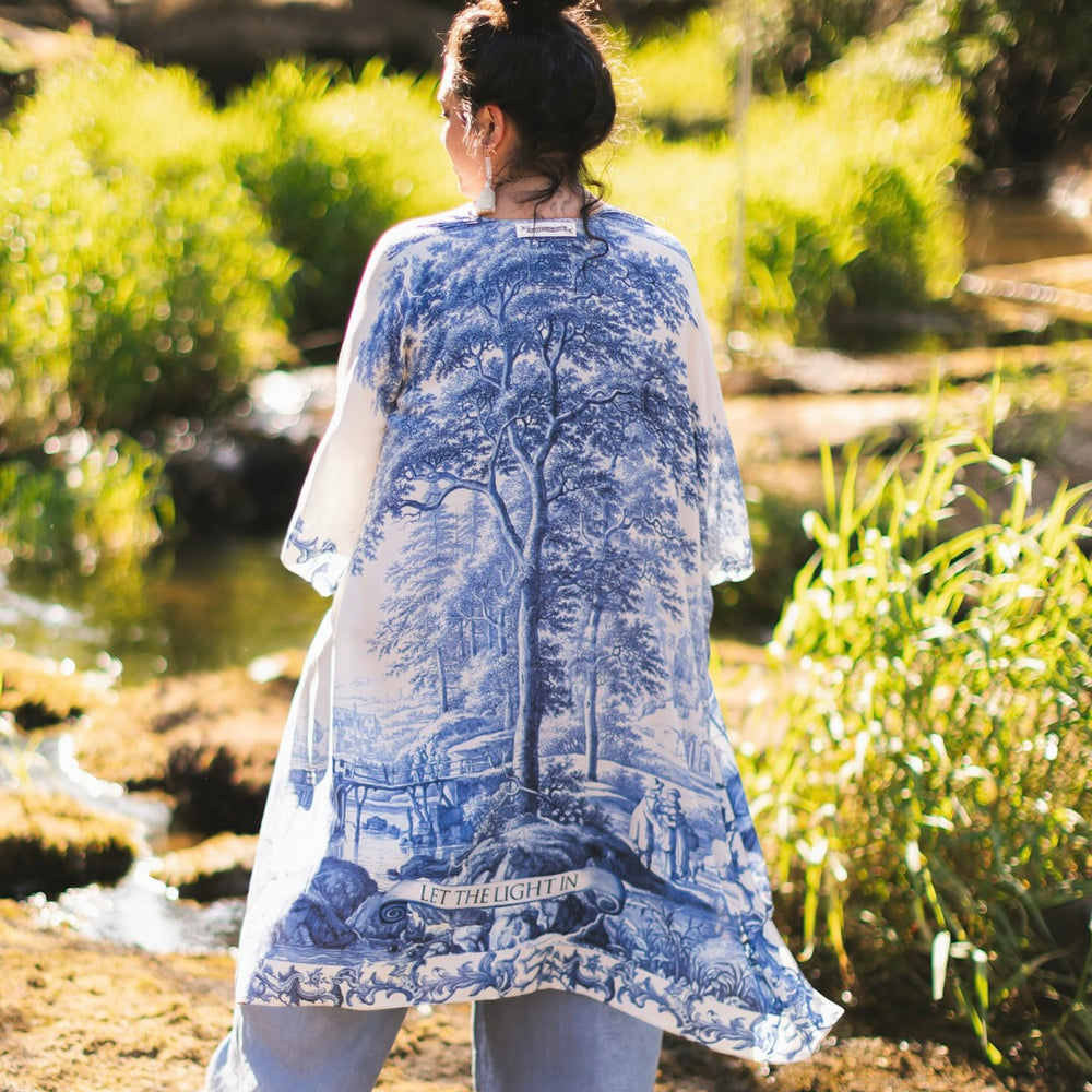 
                  
                    Model wearing Let the Light In Goddess kimono duster featuring print of Delft blue and white landscape pottery, and positive message of light and hope - Market of Stars
                  
                