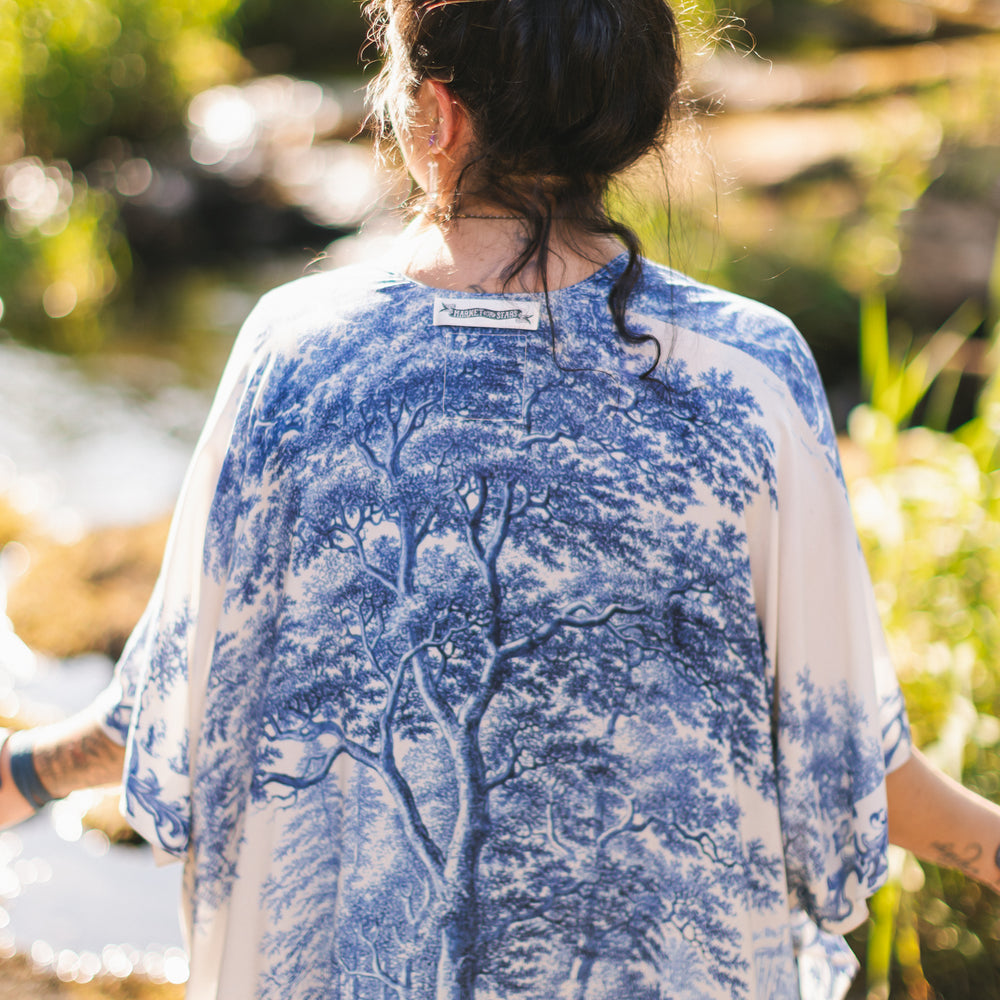 
                  
                    Model wearing Let the Light In Goddess kimono duster featuring print of Delft blue and white landscape pottery, and positive message of light and hope - Market of Stars
                  
                