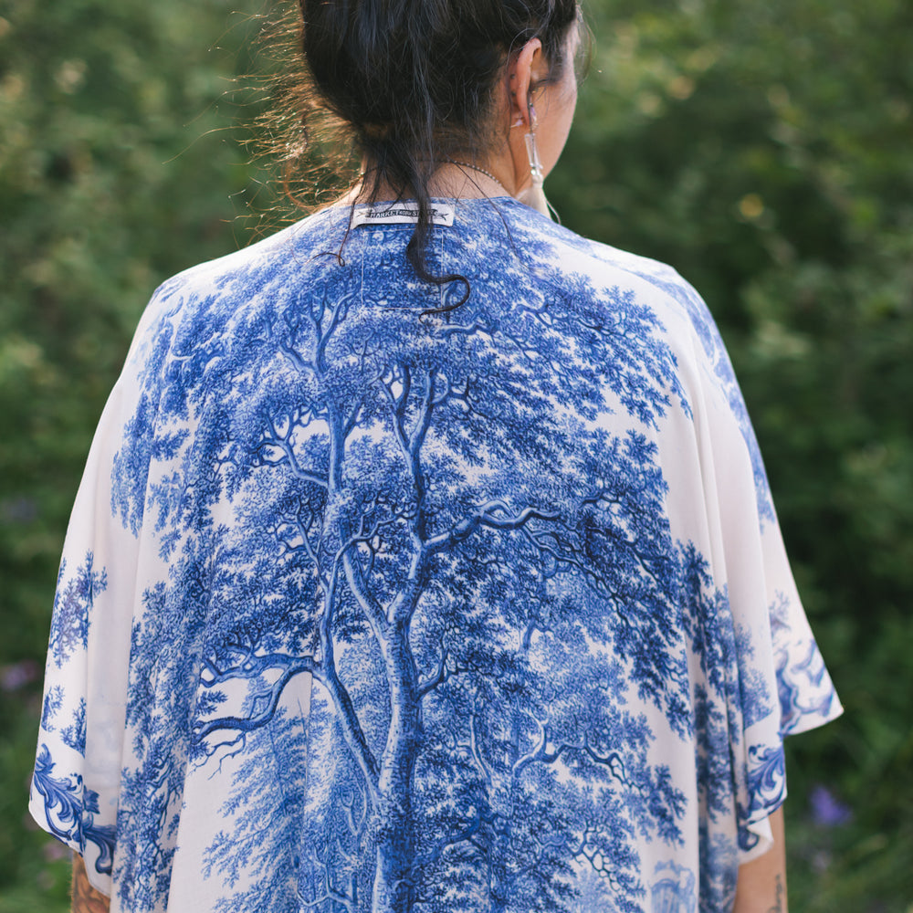 
                  
                    Model wearing Let the Light In Goddess kimono duster featuring print of Delft blue and white landscape pottery, and positive message of light and hope - Market of Stars
                  
                