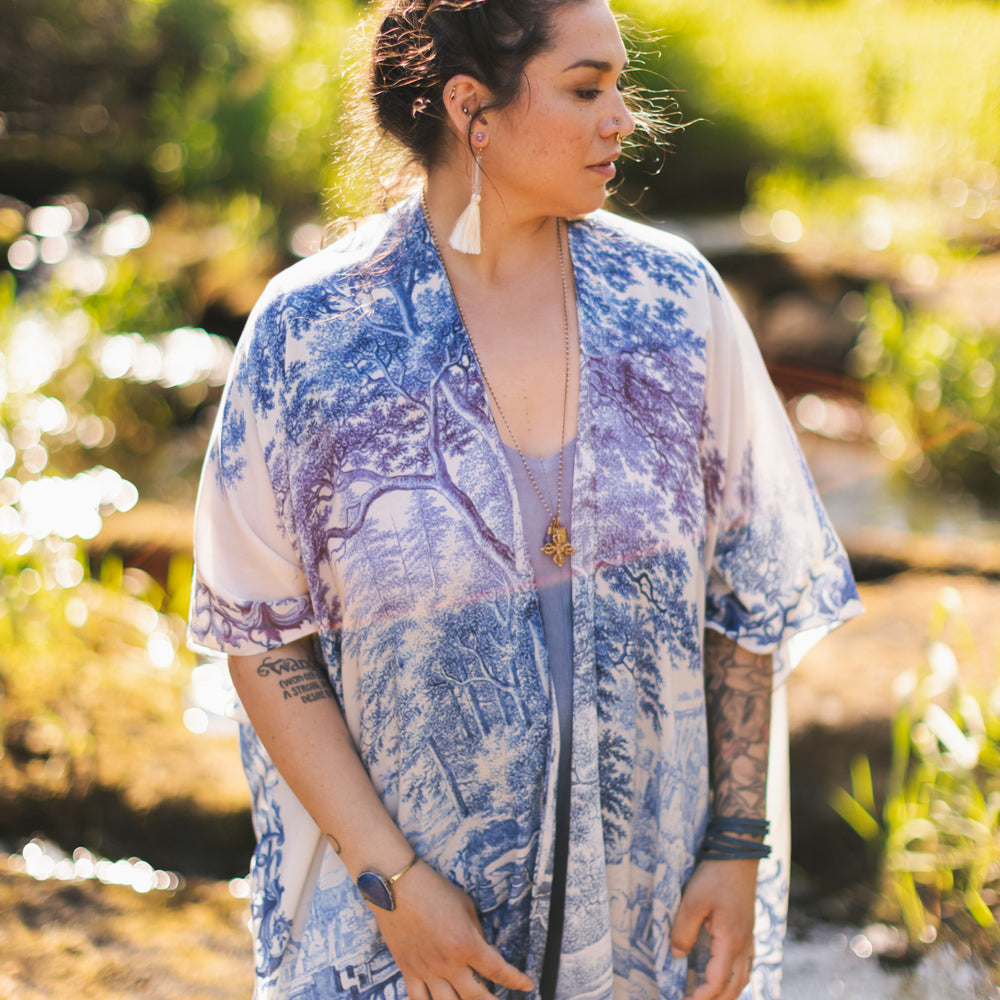 
                  
                    Model wearing Let the Light In Goddess kimono duster featuring print of Delft blue and white landscape pottery, and positive message of light and hope - Market of Stars
                  
                