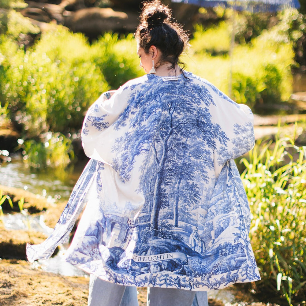 
                  
                    Model wearing Let the Light In Goddess kimono duster featuring print of Delft blue and white landscape pottery, and positive message of light and hope - Market of Stars
                  
                