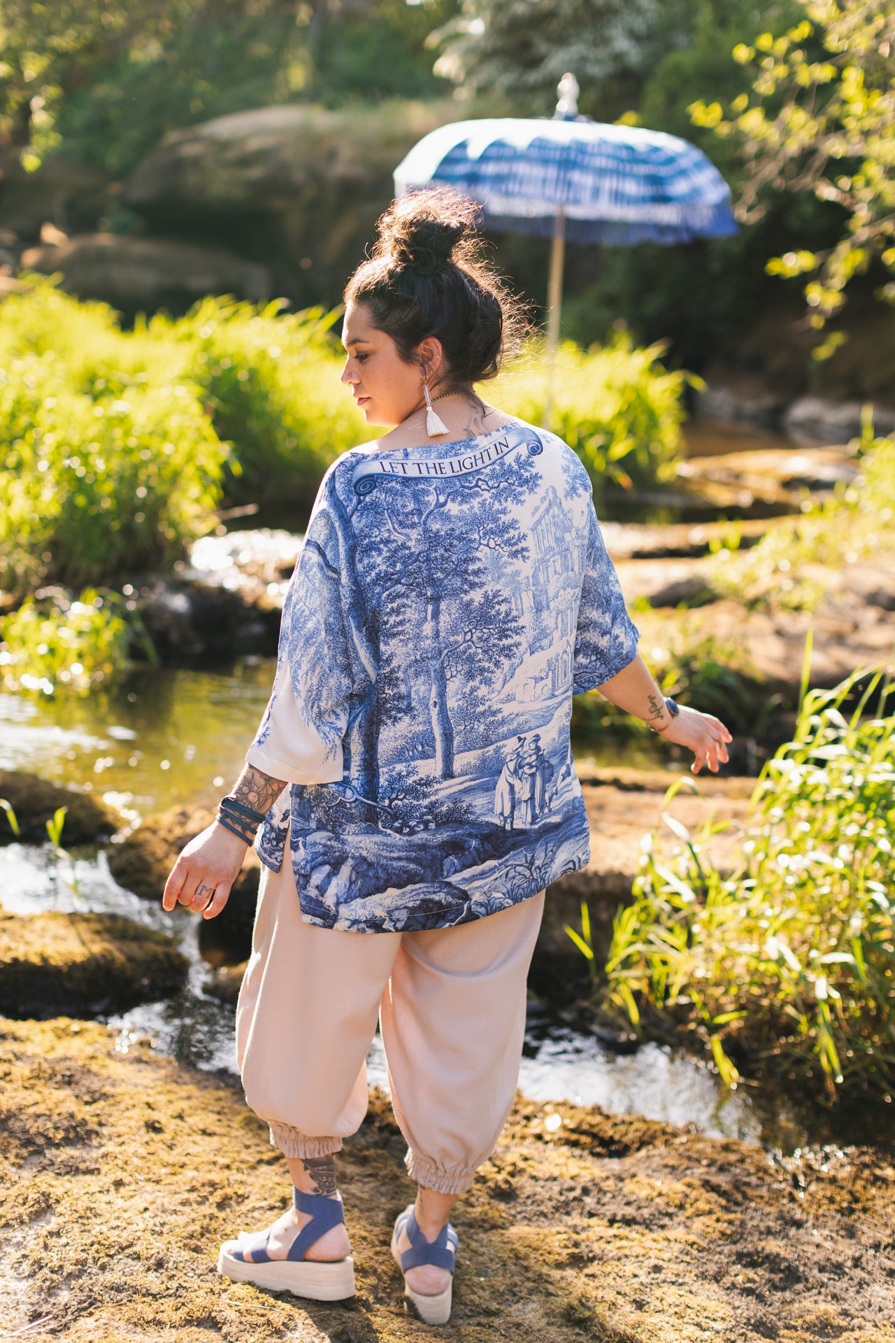 Model wearing Let the Light In bamboo viscose Luxe Tee shirt featuring print of Delft blue and white landscape pottery, and positive message of light and hope - Market of Stars
