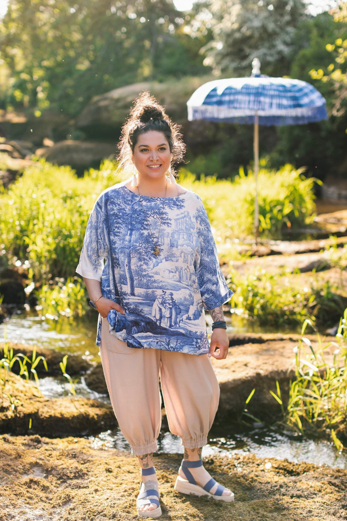 Model wearing Let the Light In bamboo viscose Luxe Tee shirt featuring print of Delft blue and white landscape pottery, and positive message of light and hope - Market of Stars