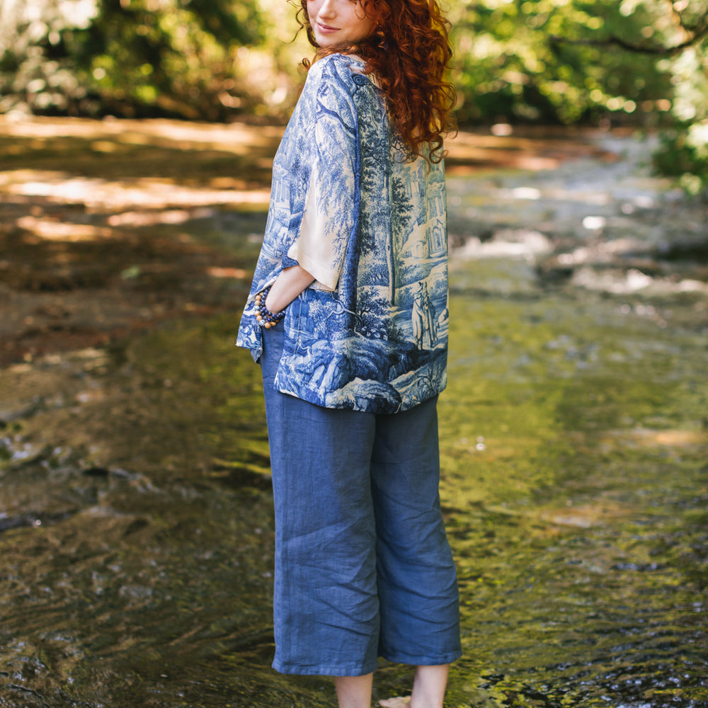 
                  
                    Model wearing Let the Light In bamboo viscose Luxe Tee shirt featuring print of Delft blue and white landscape pottery, and positive message of light and hope - Market of Stars
                  
                