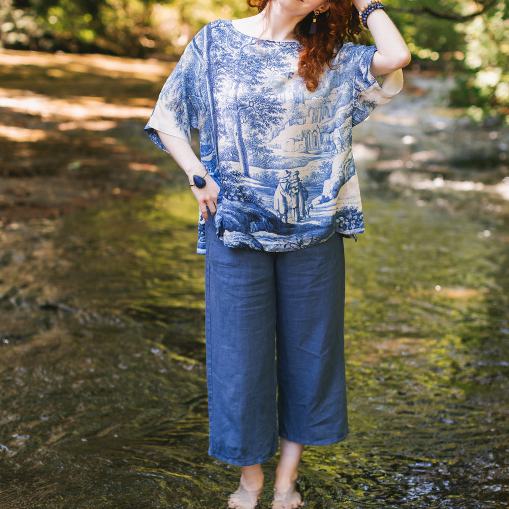 
                  
                    Model wearing Let the Light In bamboo viscose Luxe Tee shirt featuring print of Delft blue and white landscape pottery, and positive message of light and hope - Market of Stars
                  
                