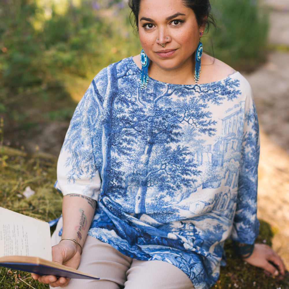 
                  
                    Model wearing Let the Light In bamboo viscose Luxe Tee shirt featuring print of Delft blue and white landscape pottery, and positive message of light and hope - Market of Stars
                  
                
