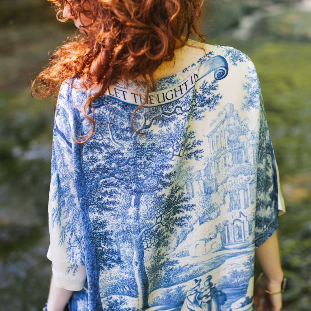 
                  
                    Model wearing Let the Light In bamboo viscose Luxe Tee shirt featuring print of Delft blue and white landscape pottery, and positive message of light and hope - Market of Stars
                  
                