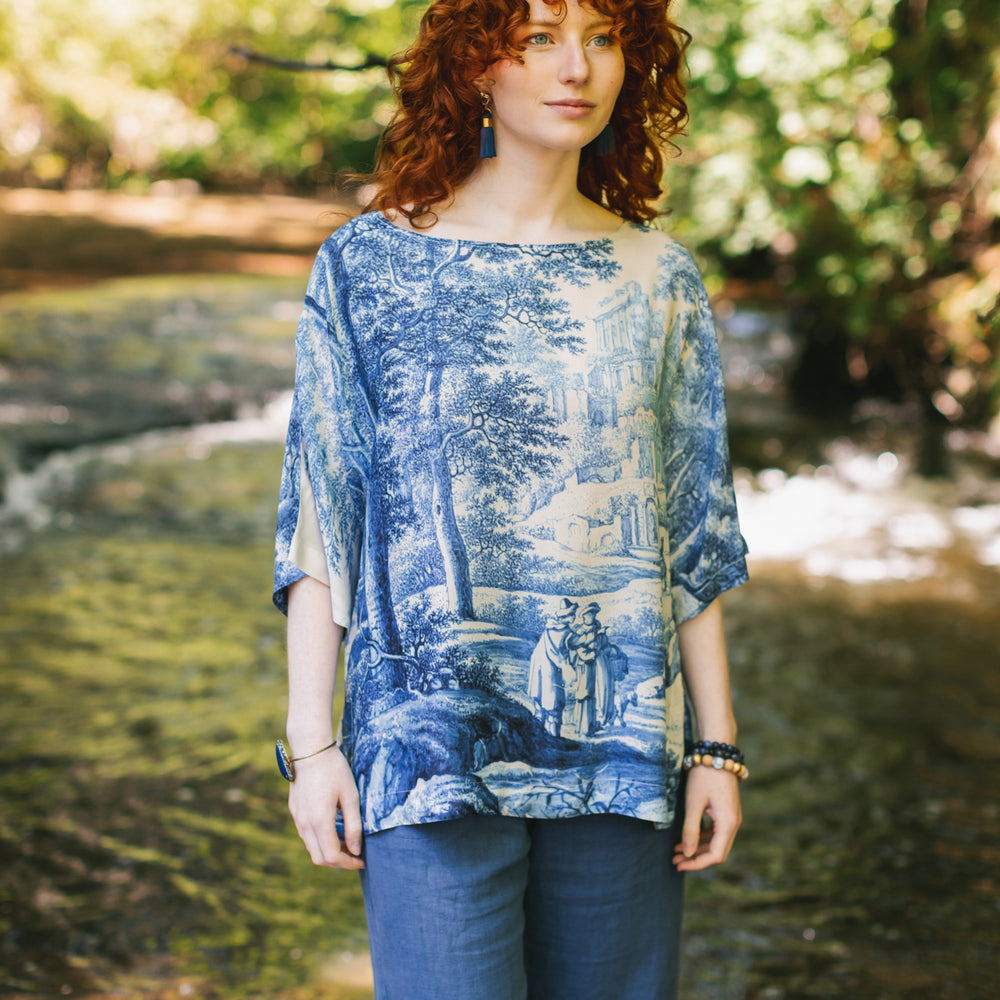 
                  
                    Model wearing Let the Light In bamboo viscose Luxe Tee shirt featuring print of Delft blue and white landscape pottery, and positive message of light and hope - Market of Stars
                  
                