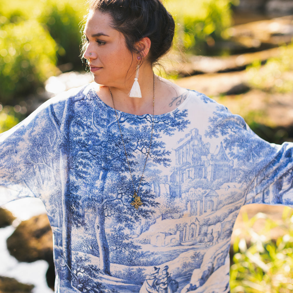 
                  
                    Model wearing Let the Light In bamboo viscose Luxe Tee shirt featuring print of Delft blue and white landscape pottery, and positive message of light and hope - Market of Stars
                  
                