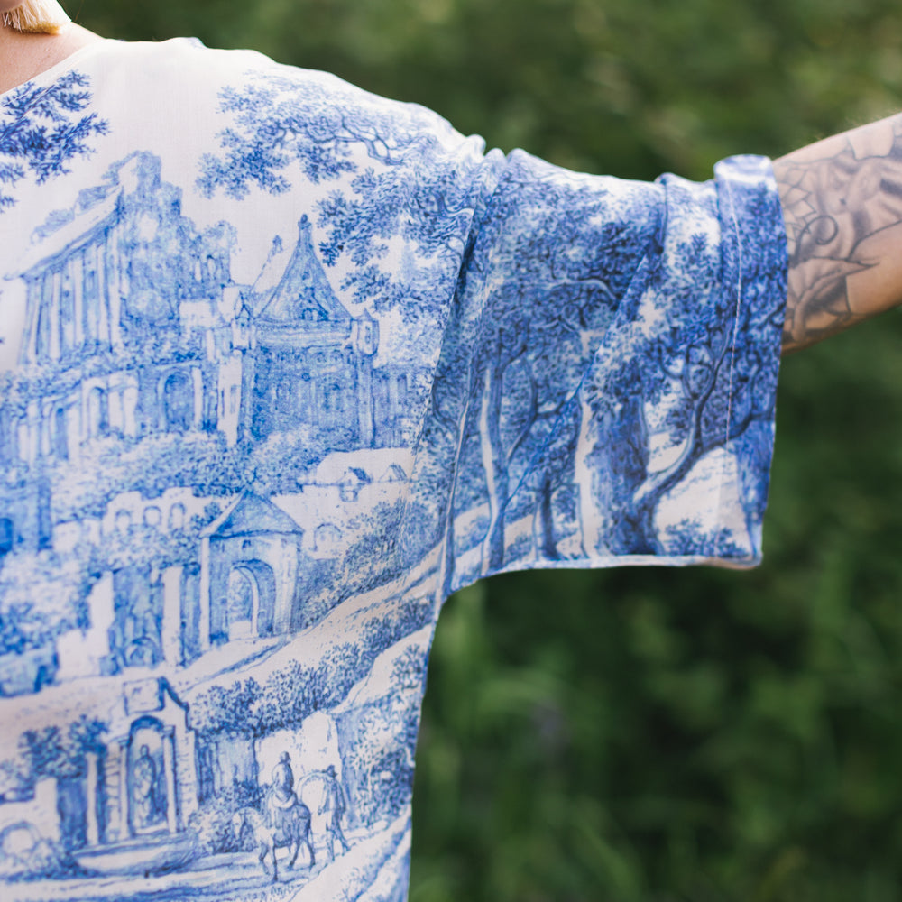 
                  
                    Model wearing Let the Light In bamboo viscose Luxe Tee shirt featuring print of Delft blue and white landscape pottery, and positive message of light and hope - Market of Stars
                  
                
