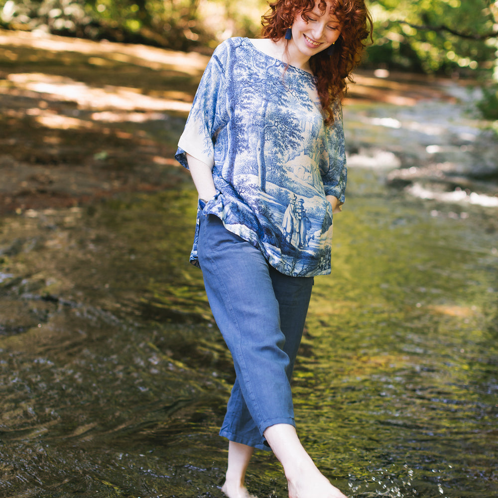 
                  
                    Model wearing Let the Light In bamboo viscose Luxe Tee shirt featuring print of Delft blue and white landscape pottery, and positive message of light and hope - Market of Stars
                  
                