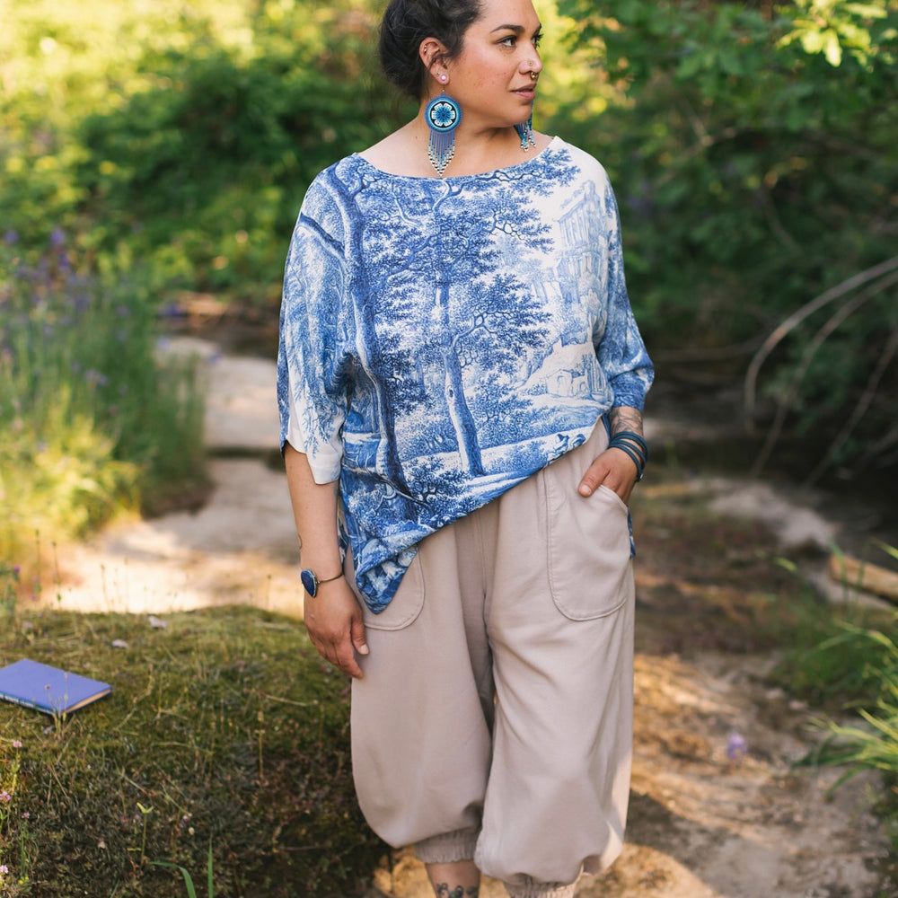 
                  
                    Model wearing Let the Light In bamboo viscose Luxe Tee shirt featuring print of Delft blue and white landscape pottery, and positive message of light and hope - Market of Stars
                  
                