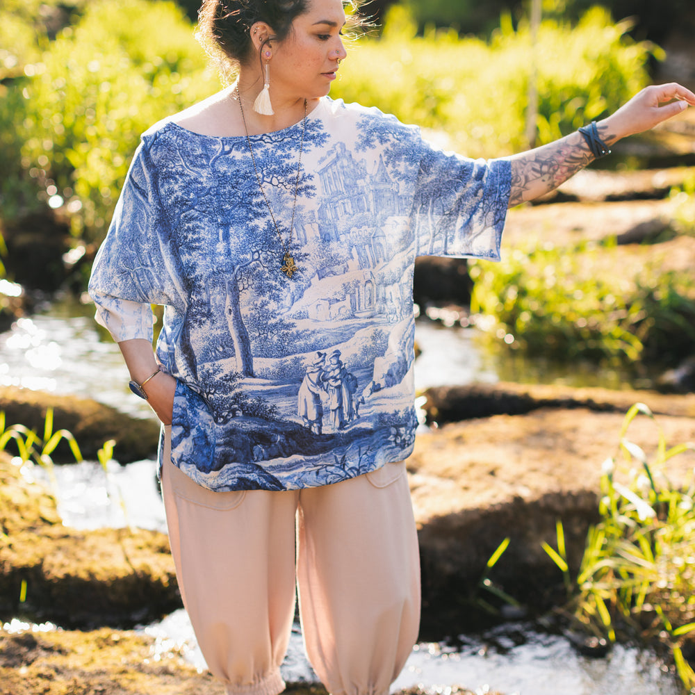 
                  
                    Model wearing Let the Light In bamboo viscose Luxe Tee shirt featuring print of Delft blue and white landscape pottery, and positive message of light and hope - Market of Stars
                  
                