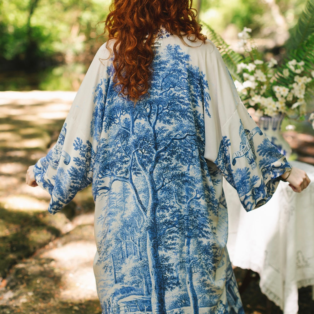 
                  
                    Model wearing Let the Light In long opera duster kimono featuring print of Delft blue and white landscape pottery, and positive message of light and hope - Market of Stars
                  
                