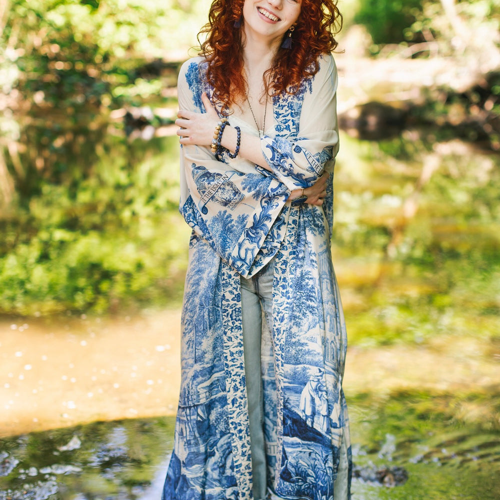 
                  
                    Model wearing Let the Light In long opera duster kimono featuring print of Delft blue and white landscape pottery, and positive message of light and hope - Market of Stars
                  
                