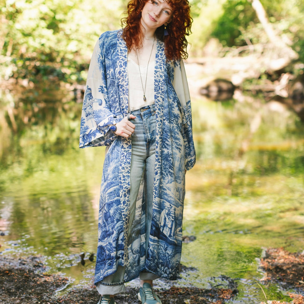 
                  
                    Model wearing Let the Light In long opera duster kimono featuring print of Delft blue and white landscape pottery, and positive message of light and hope - Market of Stars
                  
                