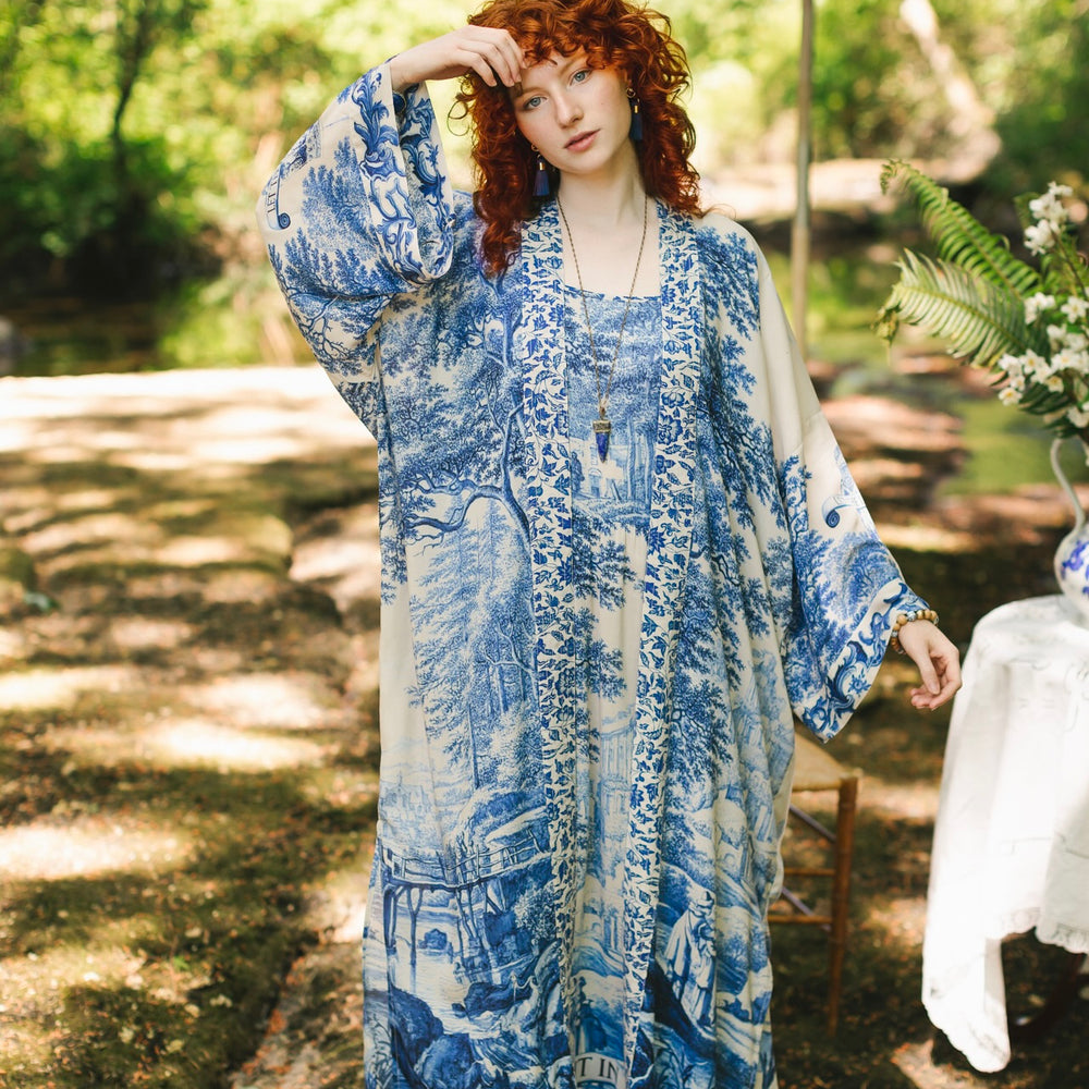 
                  
                    Model wearing Let the Light In long opera duster kimono featuring print of Delft blue and white landscape pottery, and positive message of light and hope - Market of Stars
                  
                