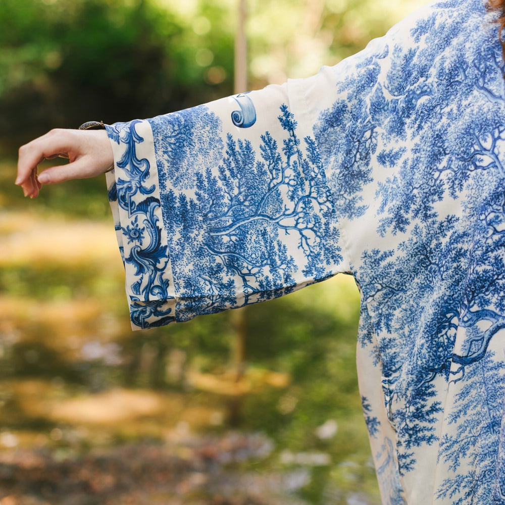 
                  
                    Model wearing Let the Light In long opera duster kimono featuring print of Delft blue and white landscape pottery, and positive message of light and hope - Market of Stars
                  
                
