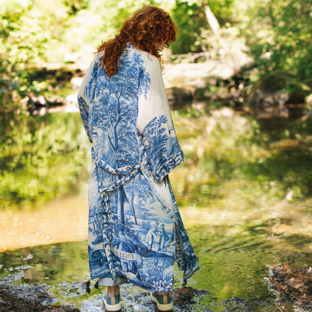 
                  
                    Model wearing Let the Light In long opera duster kimono featuring print of Delft blue and white landscape pottery, and positive message of light and hope - Market of Stars
                  
                