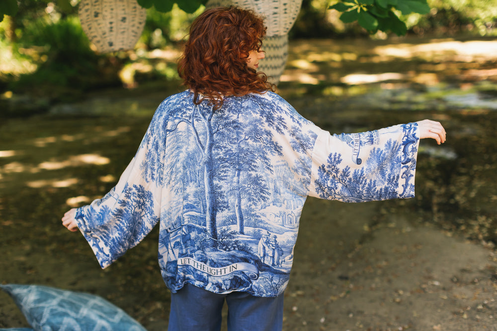 
                  
                    Model wearing Let the Light In cropped Pixie duster featuring print of Delft blue and white landscape pottery, and positive message of light and hope - Market of Stars
                  
                