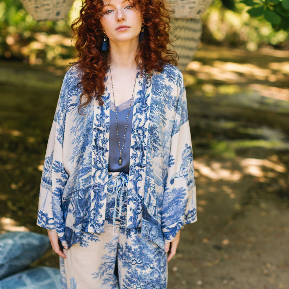 
                  
                    Model wearing Let the Light In cropped Pixie duster featuring print of Delft blue and white landscape pottery, and positive message of light and hope - Market of Stars
                  
                