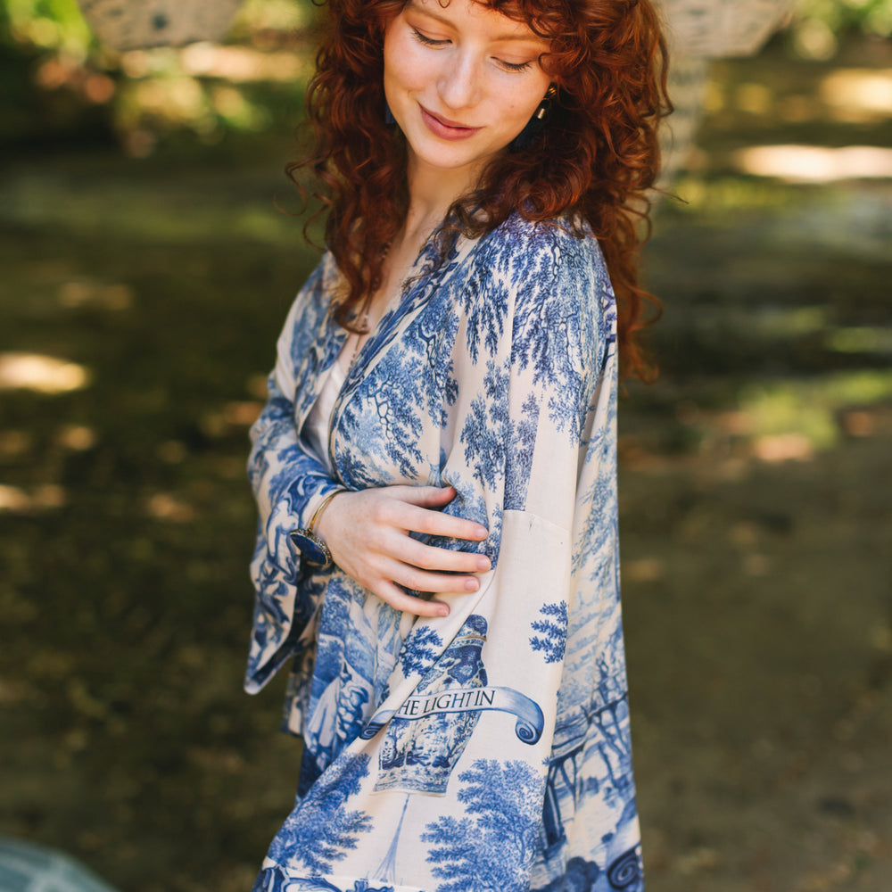 
                  
                    Model wearing Let the Light In cropped Pixie duster featuring print of Delft blue and white landscape pottery, and positive message of light and hope - Market of Stars
                  
                