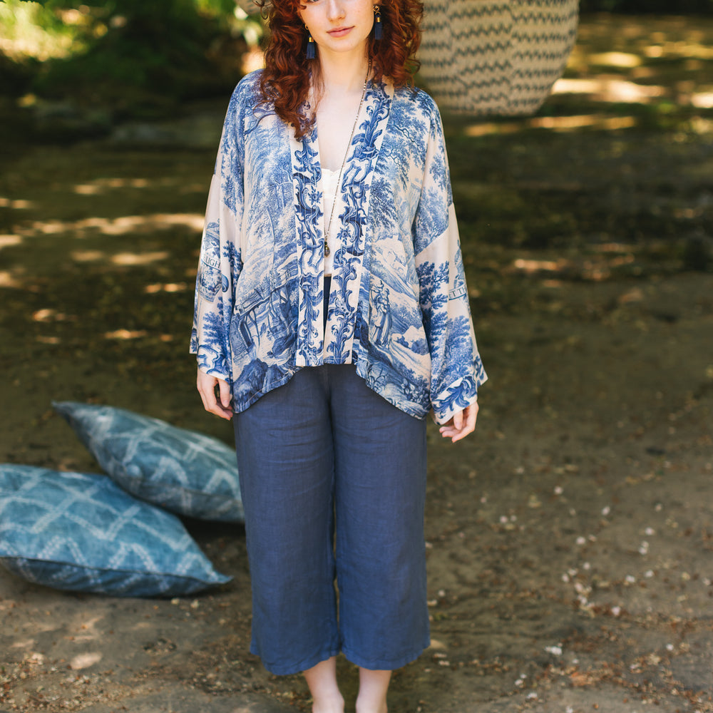 
                  
                    Model wearing Let the Light In cropped Pixie duster featuring print of Delft blue and white landscape pottery, and positive message of light and hope - Market of Stars
                  
                