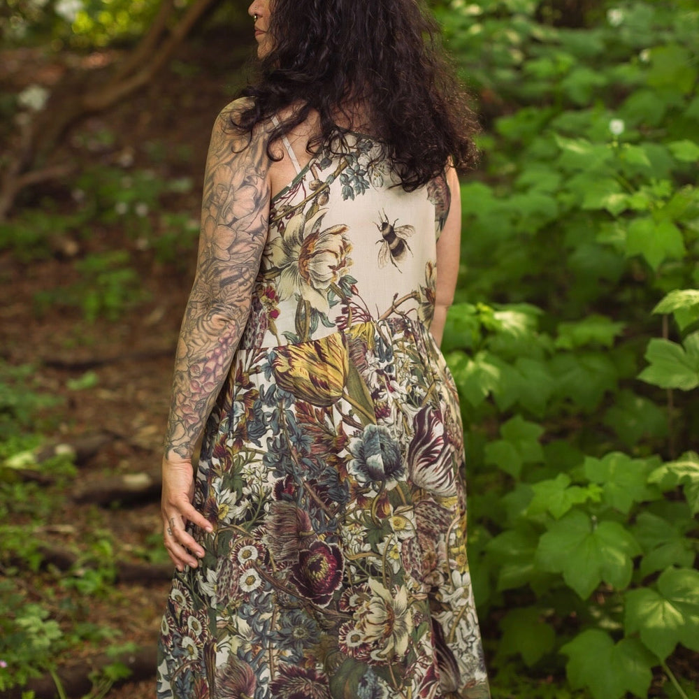 
                  
                    Model wearing Love Grows Wild Bohéme Slip Dress featuring hand-coloured 1700s botanical etchings and bumblebee detail – adjustable, flowy, and reversible – Market of Stars.
                  
                