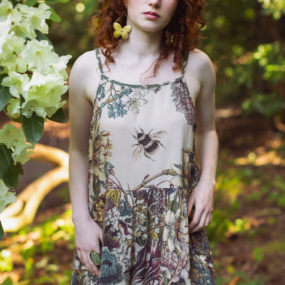 
                  
                    Model wearing Love Grows Wild Bohéme Slip Dress featuring hand-coloured 1700s botanical etchings and bumblebee detail – adjustable, flowy, and reversible – Market of Stars.
                  
                
