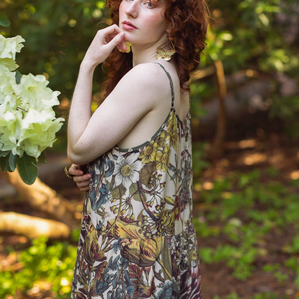 
                  
                    Model wearing Love Grows Wild Bohéme Slip Dress featuring hand-coloured 1700s botanical etchings and bumblebee detail – adjustable, flowy, and reversible – Market of Stars.
                  
                