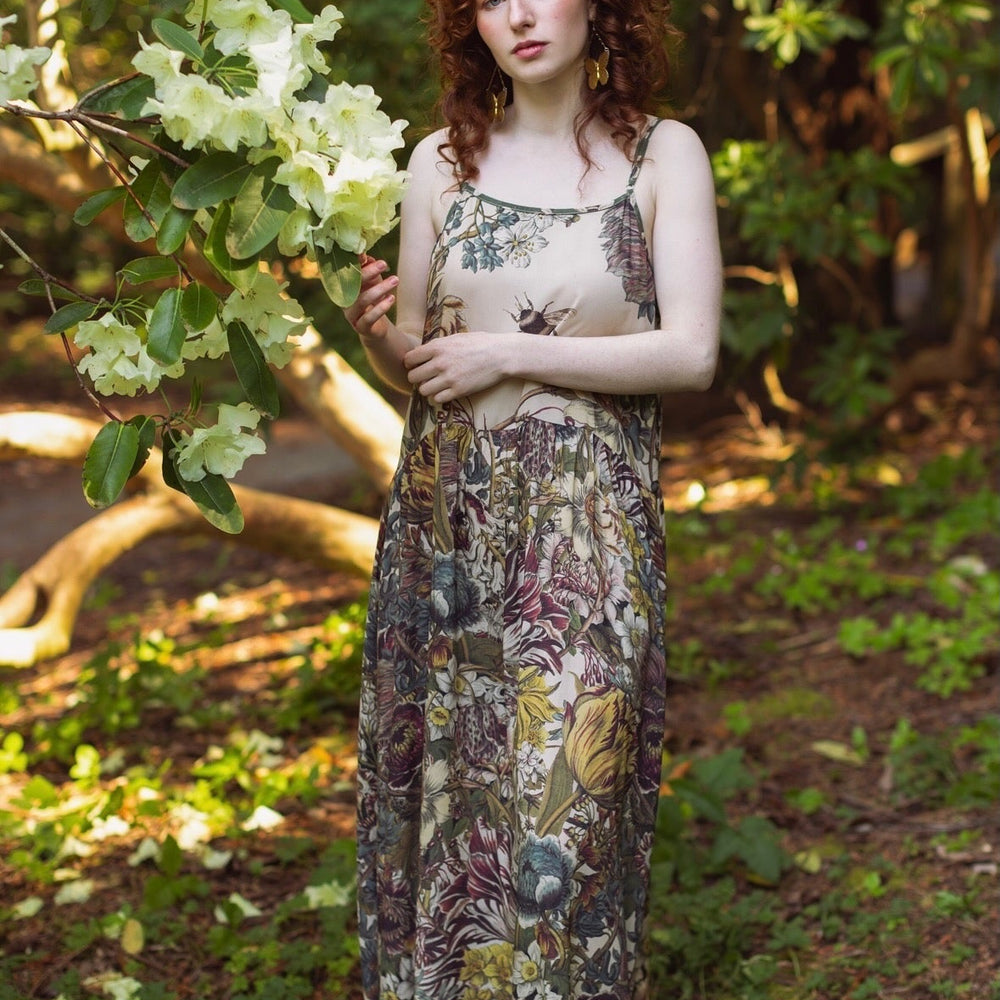 
                  
                    Model wearing Love Grows Wild Bohéme Slip Dress featuring hand-coloured 1700s botanical etchings and bumblebee detail – adjustable, flowy, and reversible – Market of Stars.
                  
                