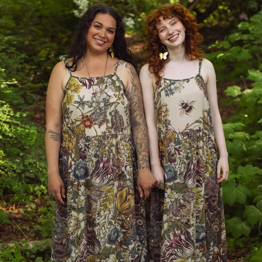 
                  
                    Model wearing Love Grows Wild Bohéme Slip Dress featuring hand-coloured 1700s botanical etchings and bumblebee detail – adjustable, flowy, and reversible – Market of Stars.
                  
                