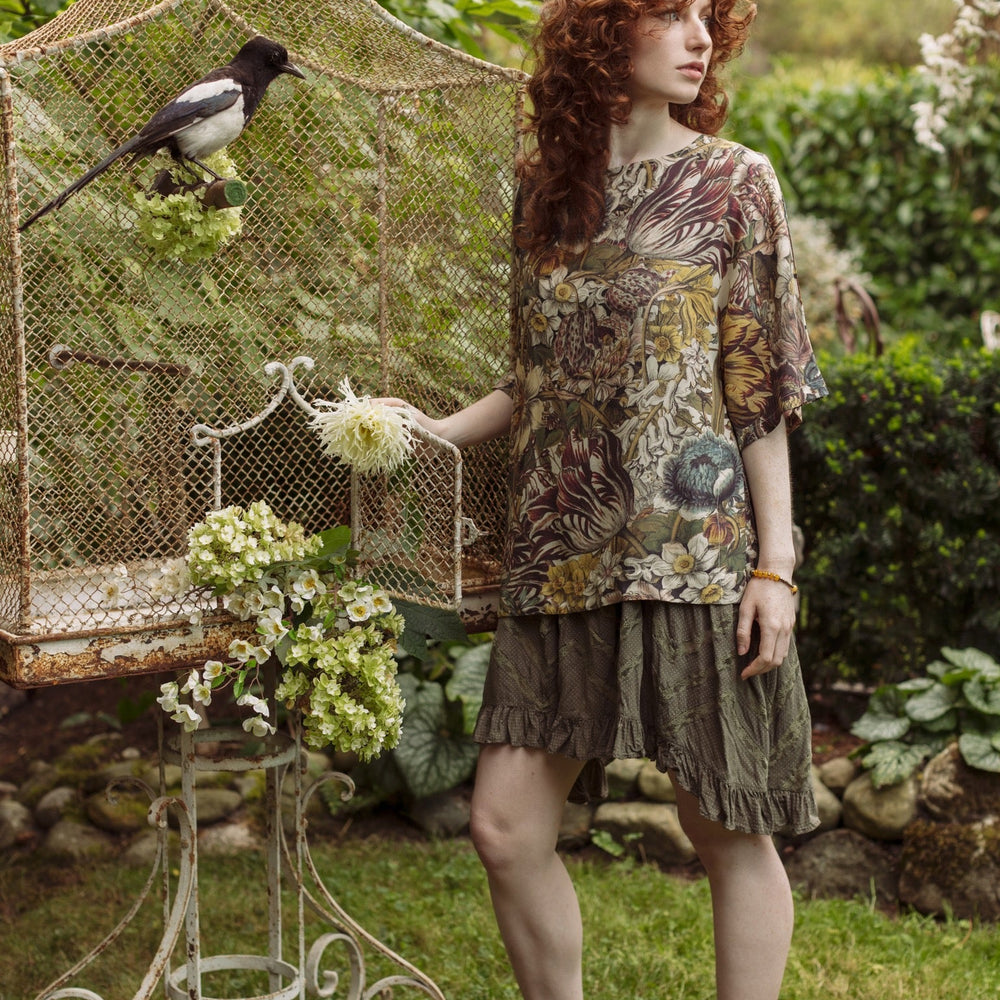 
                  
                    Model wearing the Love Grows Wild Luxe Tee featuring lush floral etchings inspired by 1700s botanical art with hidden bee trim detail – Market of Stars.
                  
                
