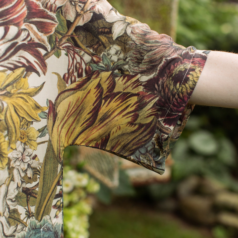 
                  
                    Model wearing the Love Grows Wild Luxe Tee featuring lush floral etchings inspired by 1700s botanical art with hidden bee trim detail – Market of Stars.
                  
                