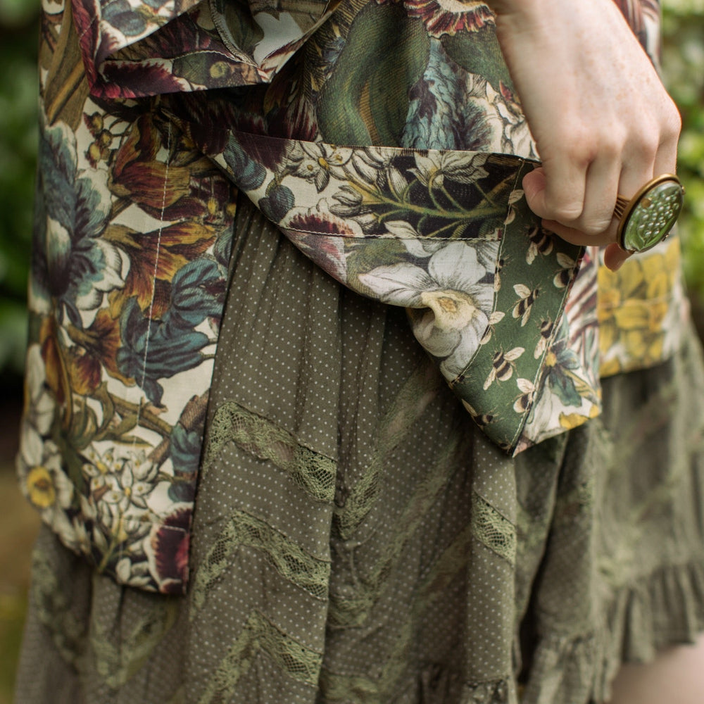 
                  
                    Model wearing the Love Grows Wild Luxe Tee featuring lush floral etchings inspired by 1700s botanical art with hidden bee trim detail – Market of Stars.
                  
                