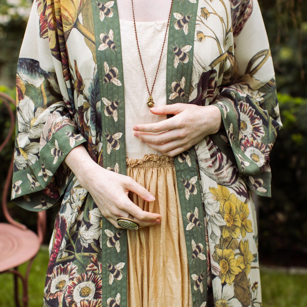 
                  
                    Model wearing kimono featuring 1700s March floral etchings and charming bumblebee trim inspired by vintage seed catalogues – Market of Stars.
                  
                