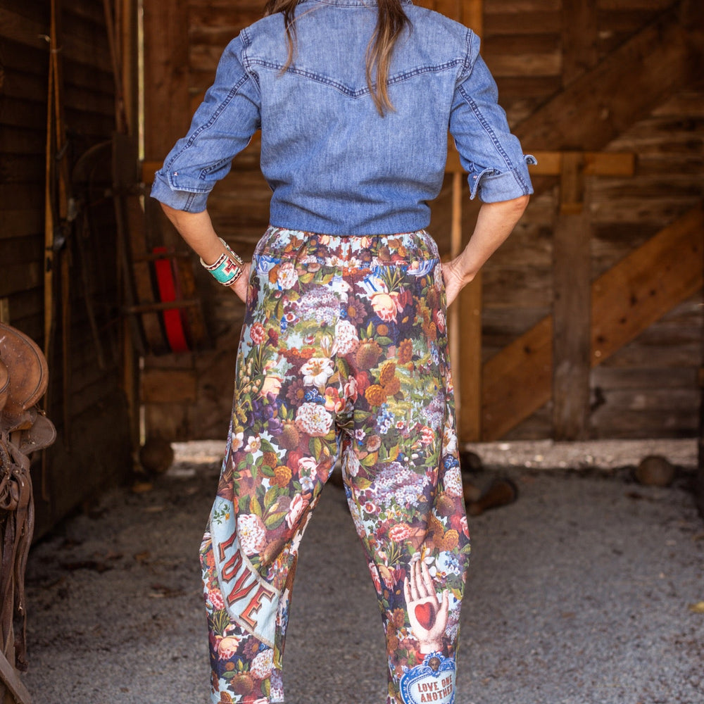 
                  
                    Model wearing linen blend artist pants with 1854 floral art, heart-in-hand symbol, and “Love one another” handwritten script – Market of Stars.
                  
                