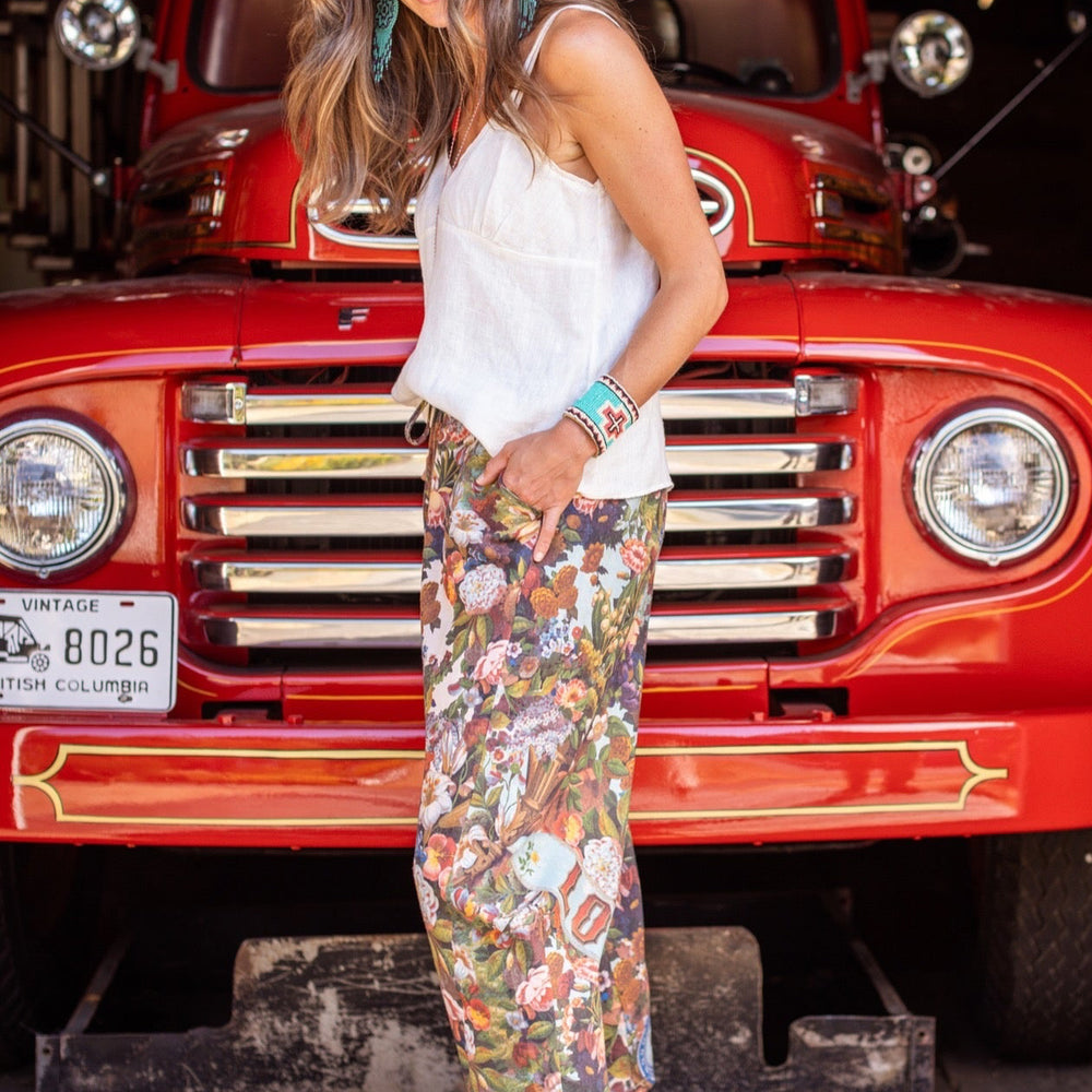 
                  
                    Model wearing linen blend artist pants with 1854 floral art, heart-in-hand symbol, and “Love one another” handwritten script – Market of Stars.
                  
                