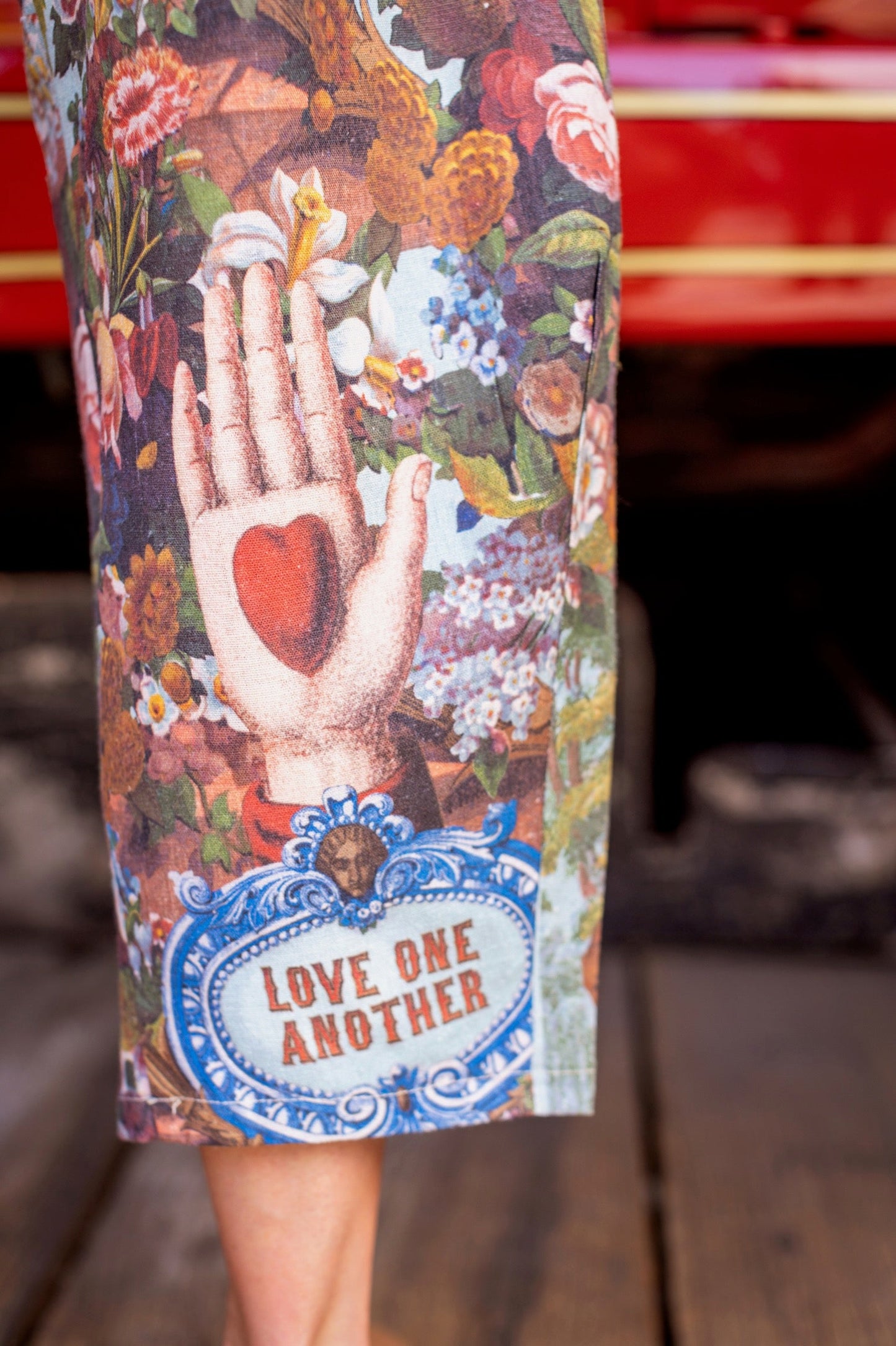 Model wearing linen blend artist pants with 1854 floral art, heart-in-hand symbol, and “Love one another” handwritten script – Market of Stars.