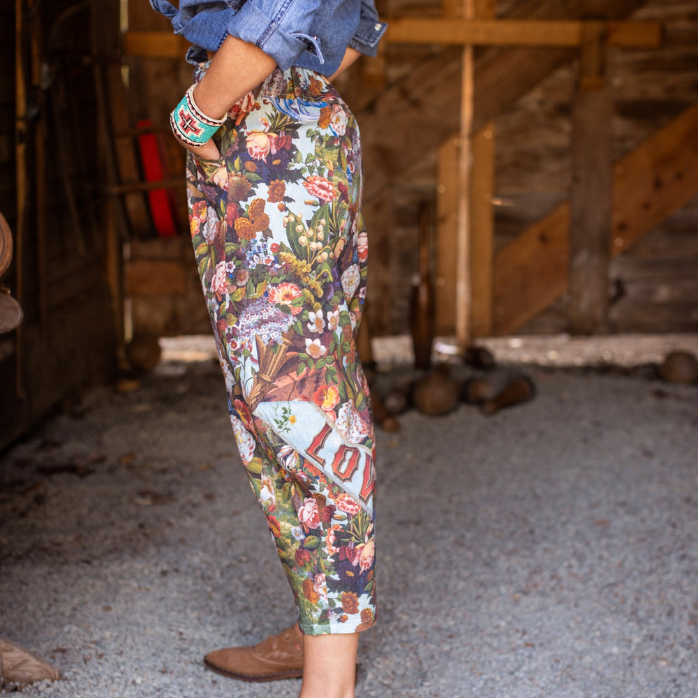 
                  
                    Model wearing linen blend artist pants with 1854 floral art, heart-in-hand symbol, and “Love one another” handwritten script – Market of Stars.
                  
                