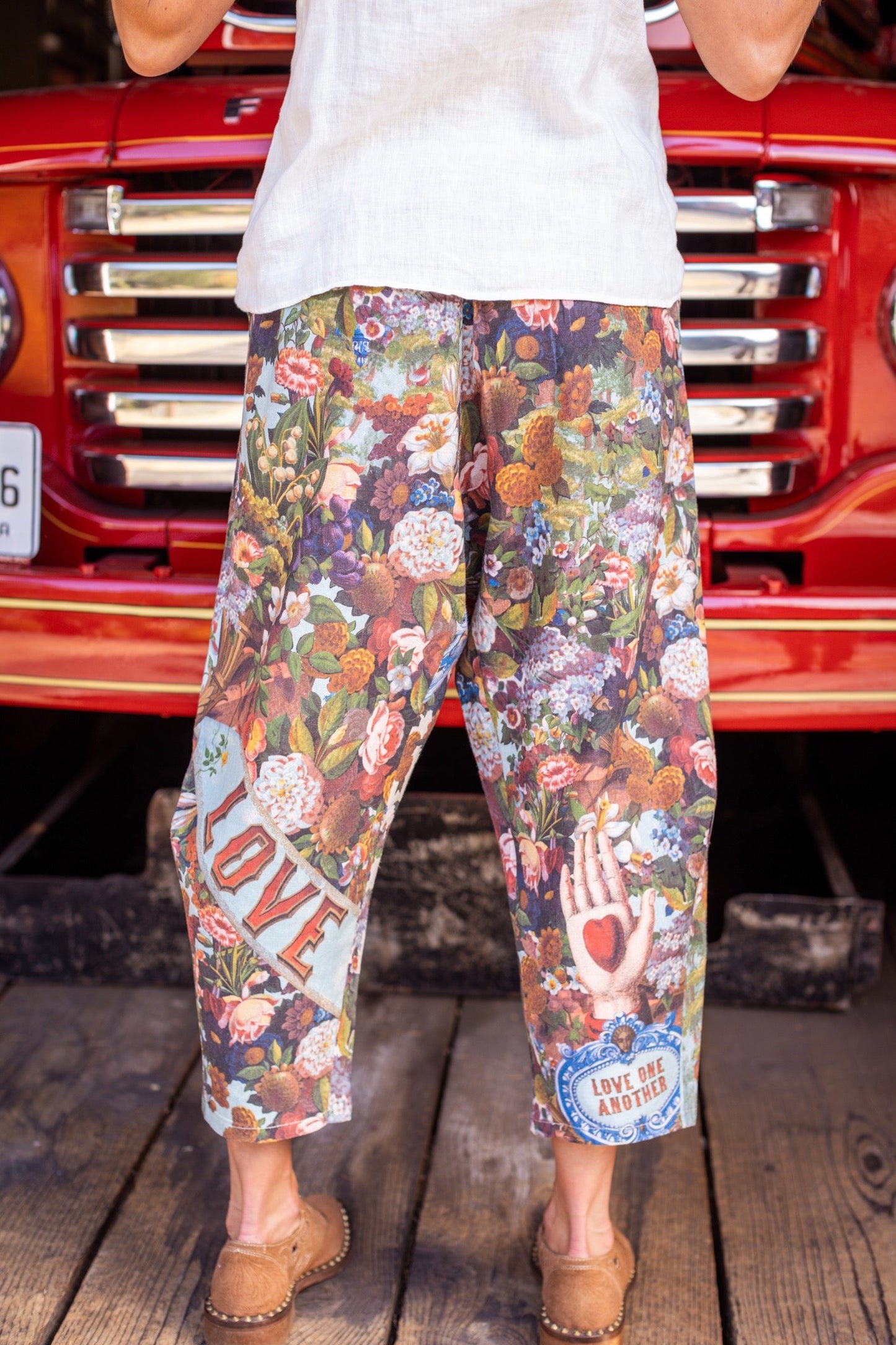 Model wearing linen blend artist pants with 1854 floral art, heart-in-hand symbol, and “Love one another” handwritten script – Market of Stars.